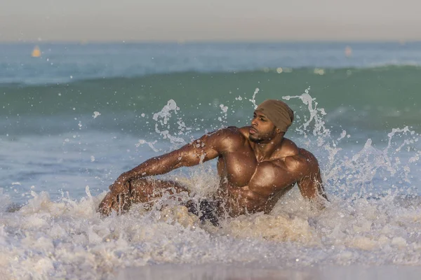 Человек сидит в воде на краю пляжа — стоковое фото