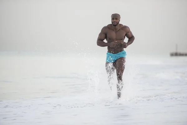 Mann läuft am Strand im Wasser — Stockfoto