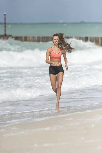 Vackra Europeiska flicka kör på stranden mot kameran — Stockfoto
