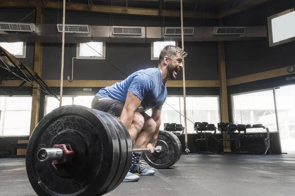 Strong white man deadlift in cross-fit  gym with an aggressive scream — Stock Photo, Image