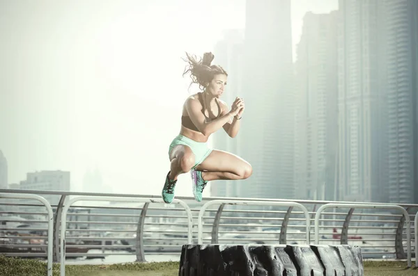 Stark atletisk Middle Eastern flicka hoppar högt över ett stort däck — Stockfoto