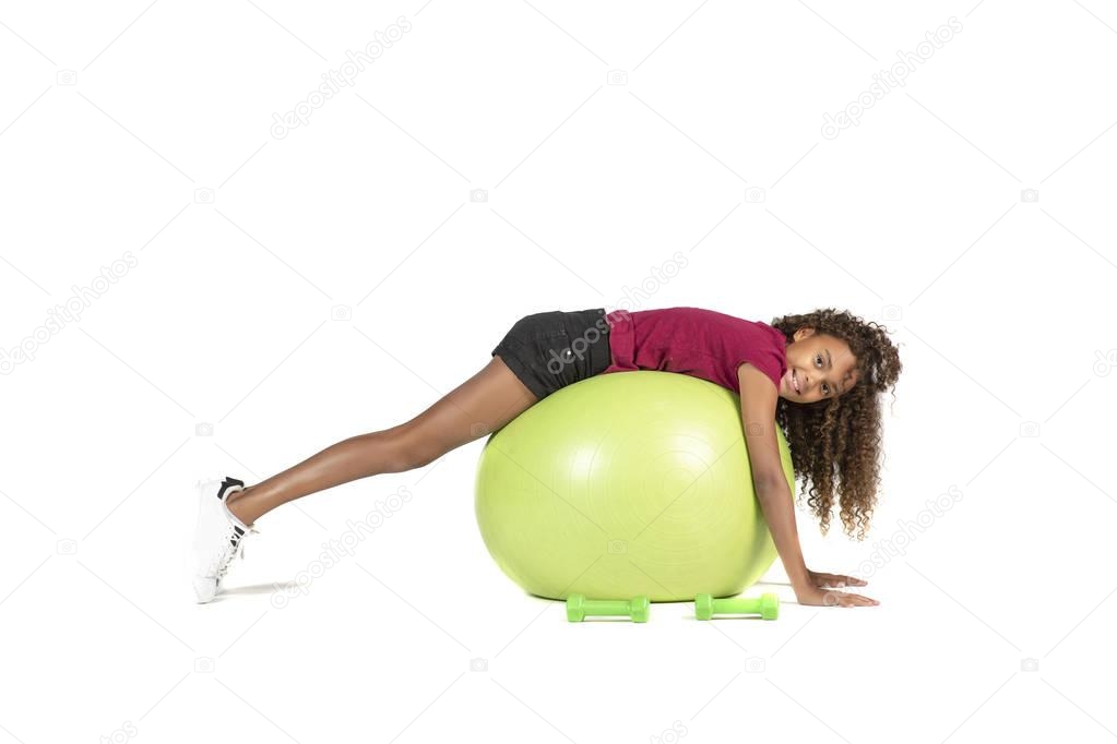 Young playful child or Pre teen biracial girl with brown curly hair  playing or exercising on a large rubber ball