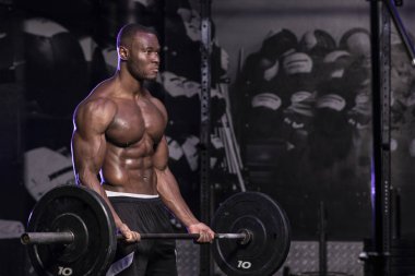 Kaslı, Afrikalı, üstsüz, terli erkek vücut geliştirme sporcusu. Kaslı, kirli bir spor salonunda halter kıvrımları yapıyor. 