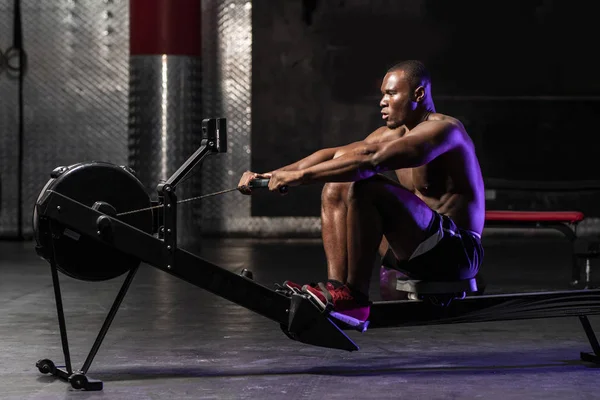Μυώδης Αφρο Αμερικανός Ημίγυμνος Αθλητής Bodybuilding Μια Μηχανή Κωπηλασίας Ένα — Φωτογραφία Αρχείου