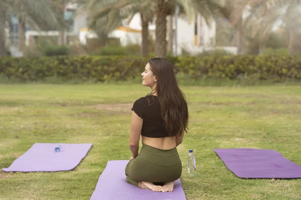 Girl in yoga pose with waves crashing over her legs on beach Stock