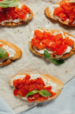 Yumuşak peynir, fesleğen ve Kağıt arka plan üzerinde domates Bruschetta