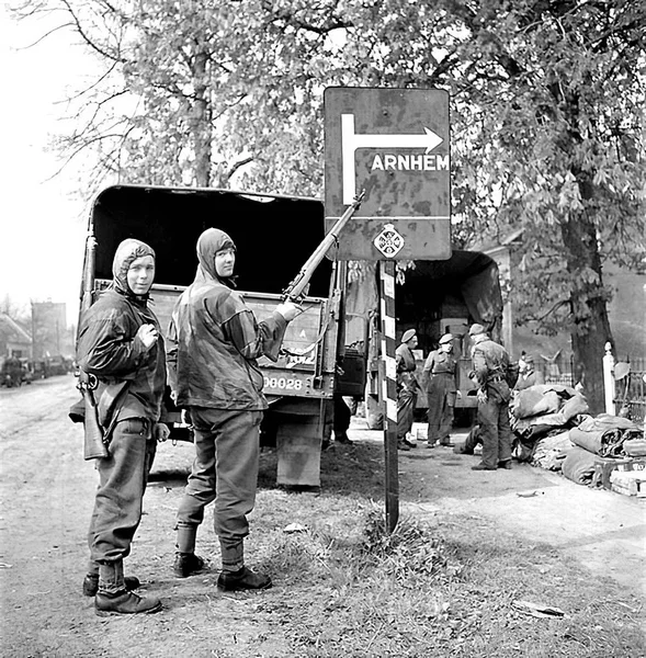 The liberation of The Netherlands. Private George Pope and Private Dennis Townsend point with rifles at road sign showing Arnhem — Stockfoto