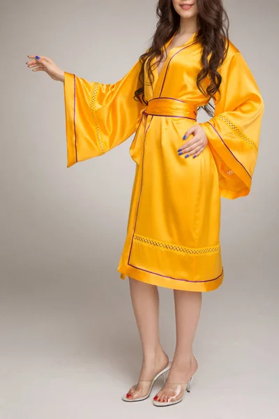 Girl in yellow silk robe, gray background