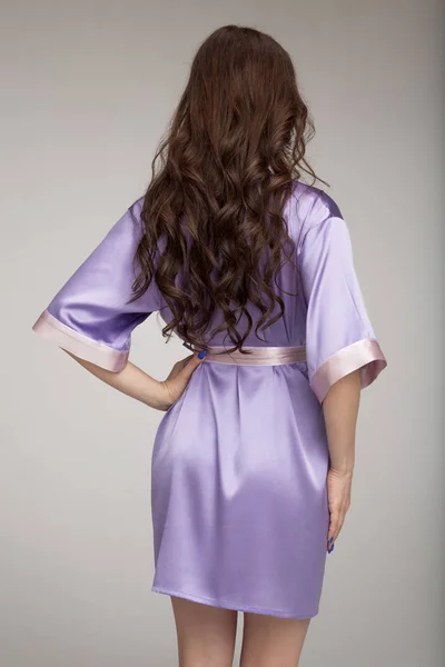 Girl in lilac silk robe, gray background