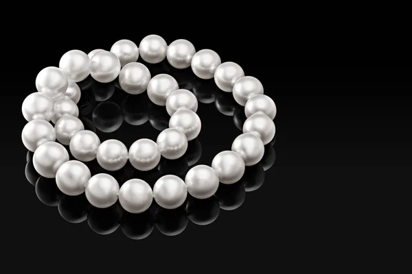 Lyxigt vitt pärlhalsband på en svart bakgrund med glänsande reflektion — Stockfoto