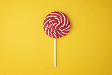 Noel lolipop şekeri sarı arka planda üstten görünüyor. Sarmal lolipop düzlüğü yakın plan yatıyordu.