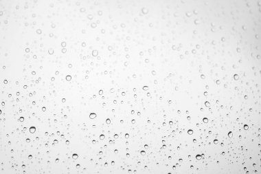 Pencere camında yağmur damlaları var. Atmosferik ışık tek renkli arkaplan ve Bokeh cinsinden yağmur damlaları