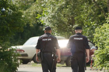 Rusya, Barnaul - 8 Temmuz 2014: İl kasabasının iki Rus polisi devriye geziyor. Polis üniformalı iki adam Rus arabalarına doğru gidiyor. Arkasına Rusça 
