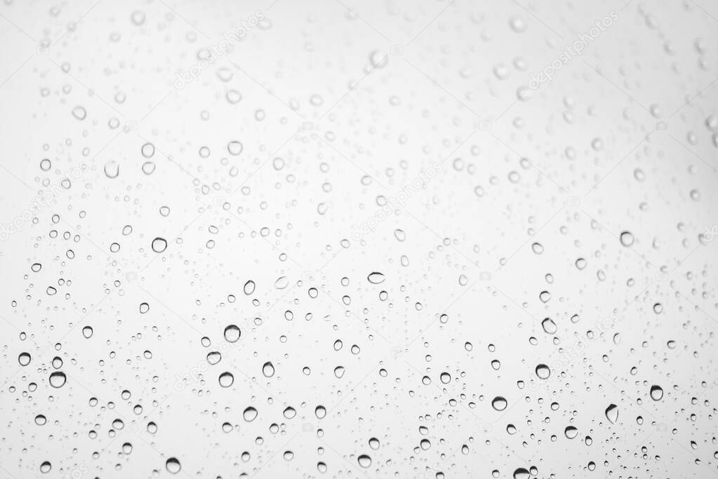 Window glass with drops of rain. Atmospheric light monochrome background with raindrops in bokeh
