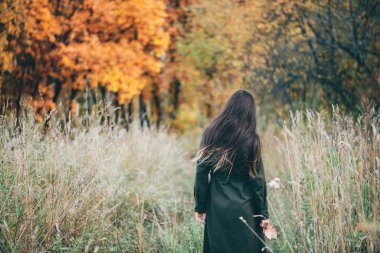 back view of reamy beautiful girl with long natural black hair in autumn forest