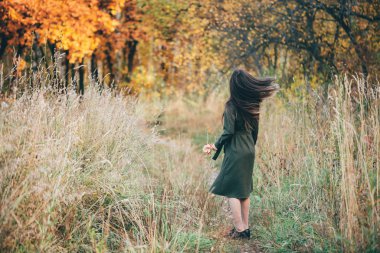back view of reamy beautiful girl with long natural black hair in autumn forest