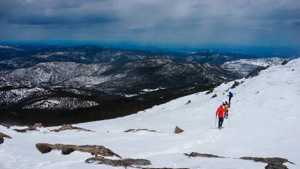 Bir grup insan hiking Colorado'da Kar ile dağın tepesinde.