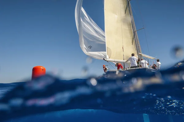 Barco à vela com spinnaker na marca windward - bóia vermelha. Vista da linha de água . — Fotografia de Stock