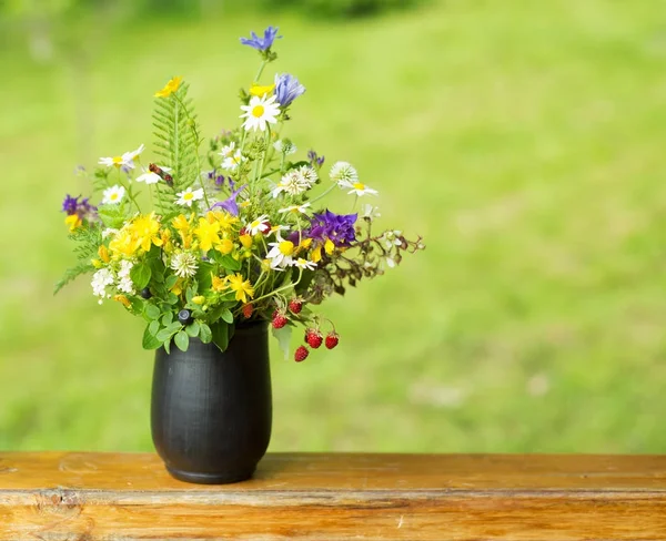 Bouquet of wildflowers and strawberry berries stand on the terrace — Stock Photo, Image