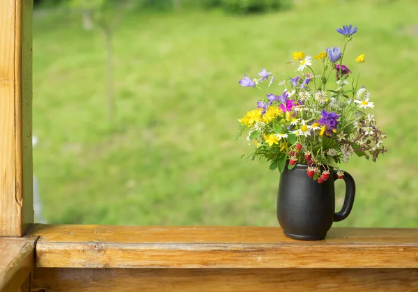 Bukett av vilda blommor och jordgubbar bär stå på terrassen — Stockfoto