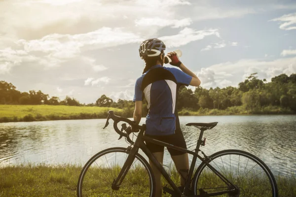 Mujer ciclista relajante beber agua del ejercicio — Foto de Stock