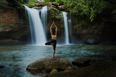 Şelalede yoga pozu veren genç bir kadın kendini rahat hissetti. T
