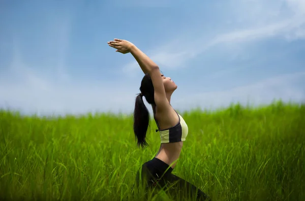 Junge Frau in Yoga-Pose auf der Wiese, fühlte sie sich entspannt. die — Stockfoto