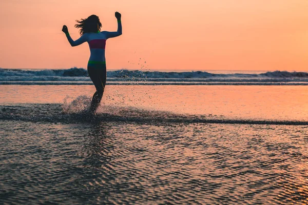 Vrouw in badmode wandelen langs de kustlijn — Stockfoto