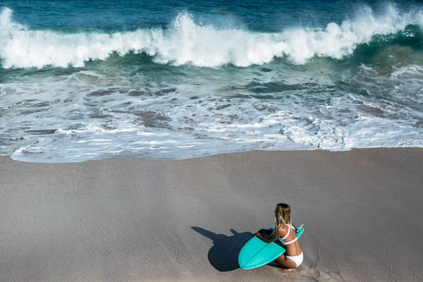 Mulher com prancha de surf sentado na praia — Fotografia de Stock