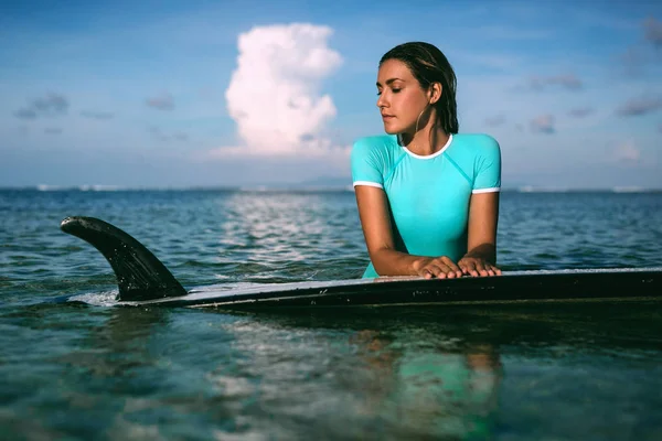 Mujer descansando sobre tabla de surf en el mar — Foto de Stock