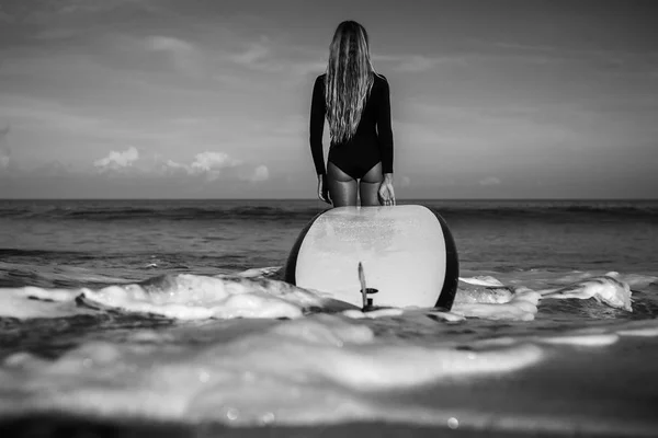 Woman with surfing board standing on beach Stock Image