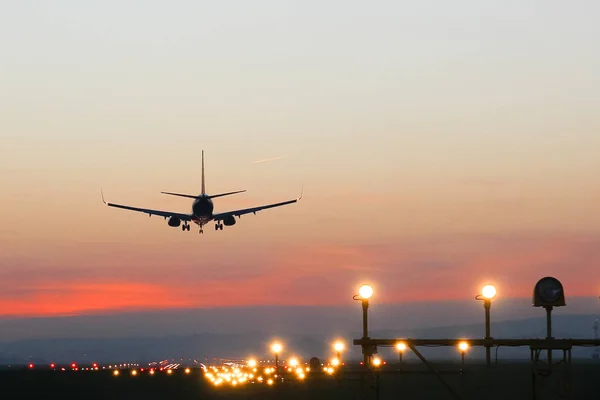 L'avion atterrit à un aérodrome sur le fond du coucher du soleil — Photo