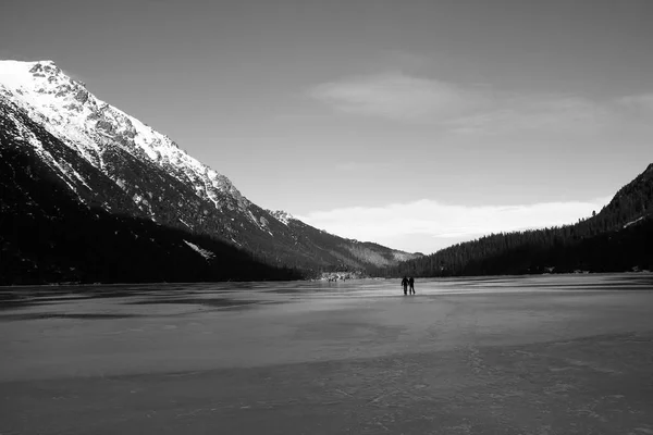 Panorama blanco y negro de lago congelado rodeado de montañas . — Foto de Stock