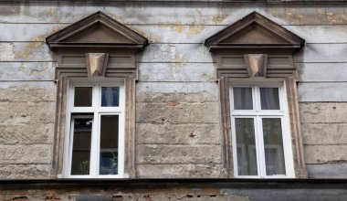 Eski yırtık pırtık tuğla bina cephesinde iki pencere