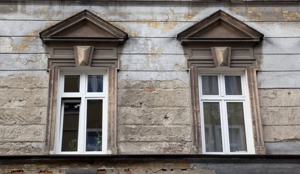 Eski yırtık pırtık tuğla bina cephesinde iki pencere