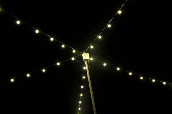 Glödlampor på sträng tråd hängande på stolpe mot bak — Stockfoto