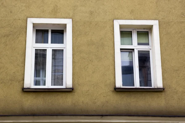 Два окна на фасаде желтого дома — стоковое фото