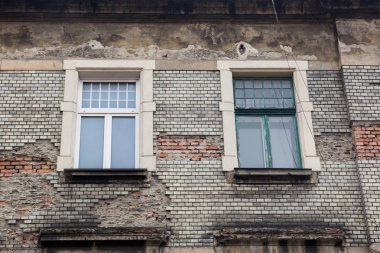 Eski hasarlı tuğla bina cephesinde iki pencere 