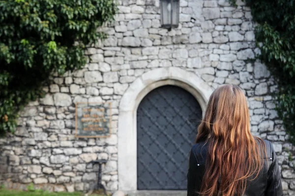 The young girl turned her back on the background of stone walls — Stock Photo, Image