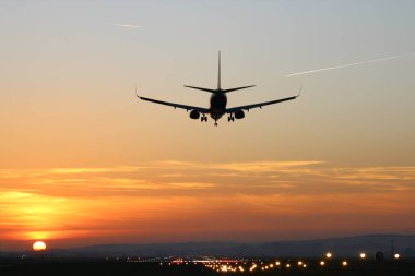 Günbatımı arka plan üzerinde bir Havaalanı'nda uçak iner