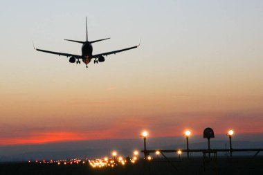 Günbatımı arka plan üzerinde bir Havaalanı'nda uçak iner
