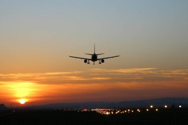 Günbatımı arka plan üzerinde bir Havaalanı'nda uçak iner