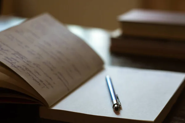 Bloc-notes ouvert avec notes manuscrites avec stylo bleu, livres dans le — Photo