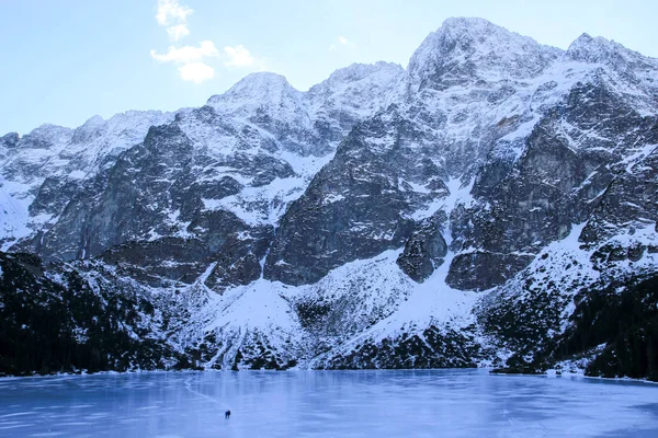 Panorama de lago congelado rodeado de montañas. La gente camina —  Fotos de Stock