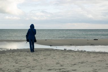 Yalnız bir kız boş bir sahilde duran ve s arıyor