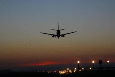 Günbatımı arka plan üzerinde bir Havaalanı'nda uçak iner