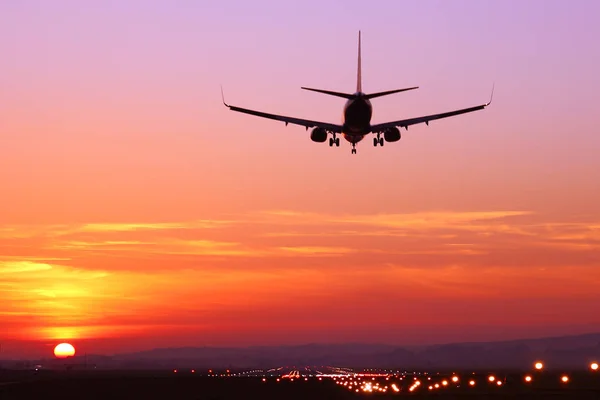 Самолет приземляется в сумерках на закате — стоковое фото