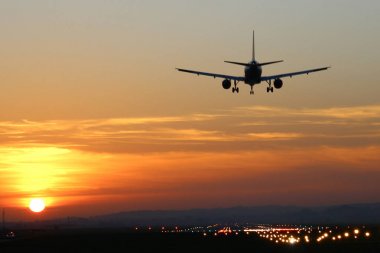 Günbatımı arka plan üzerinde bir Havaalanı'nda uçak iner