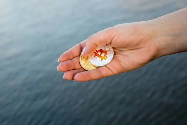 Human hand throwing bitcoins into the river — Stock Photo, Image