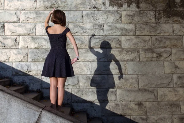 Girl dancing with her shadow on a stone wall — Stock Photo, Image